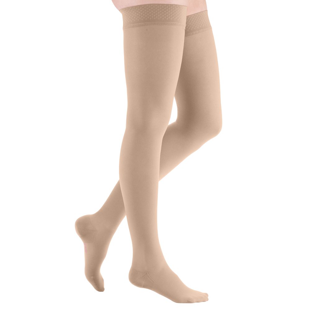 Hautfarbene Kompressionsstrümpfe am Bein. Trikotabschlussrand. Kniehoch. Blick von der Seite.