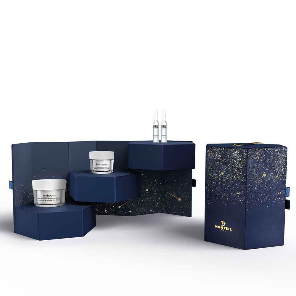 Geschenkbox mit Kosmetikprodukten. Blaue Box mit Sternenmuster und Logo. Cremes und Ampullen auf Podesten.
