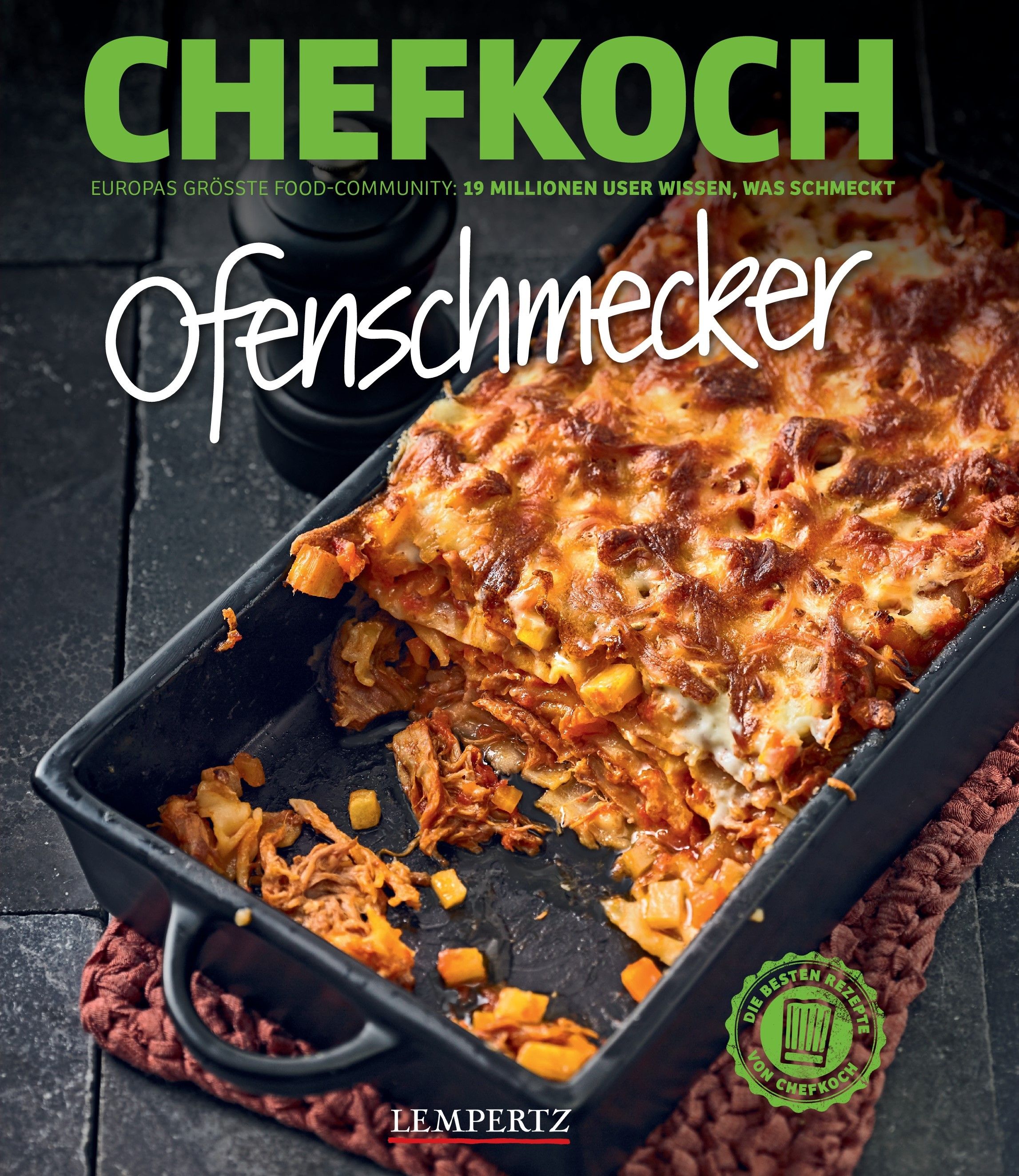 Kochbuch "Chefkoch: Ofenschmecker". Gebratene Speise in schwarzer Form. Titel und Logo deutlich sichtbar. Auf brauner Unterlage.