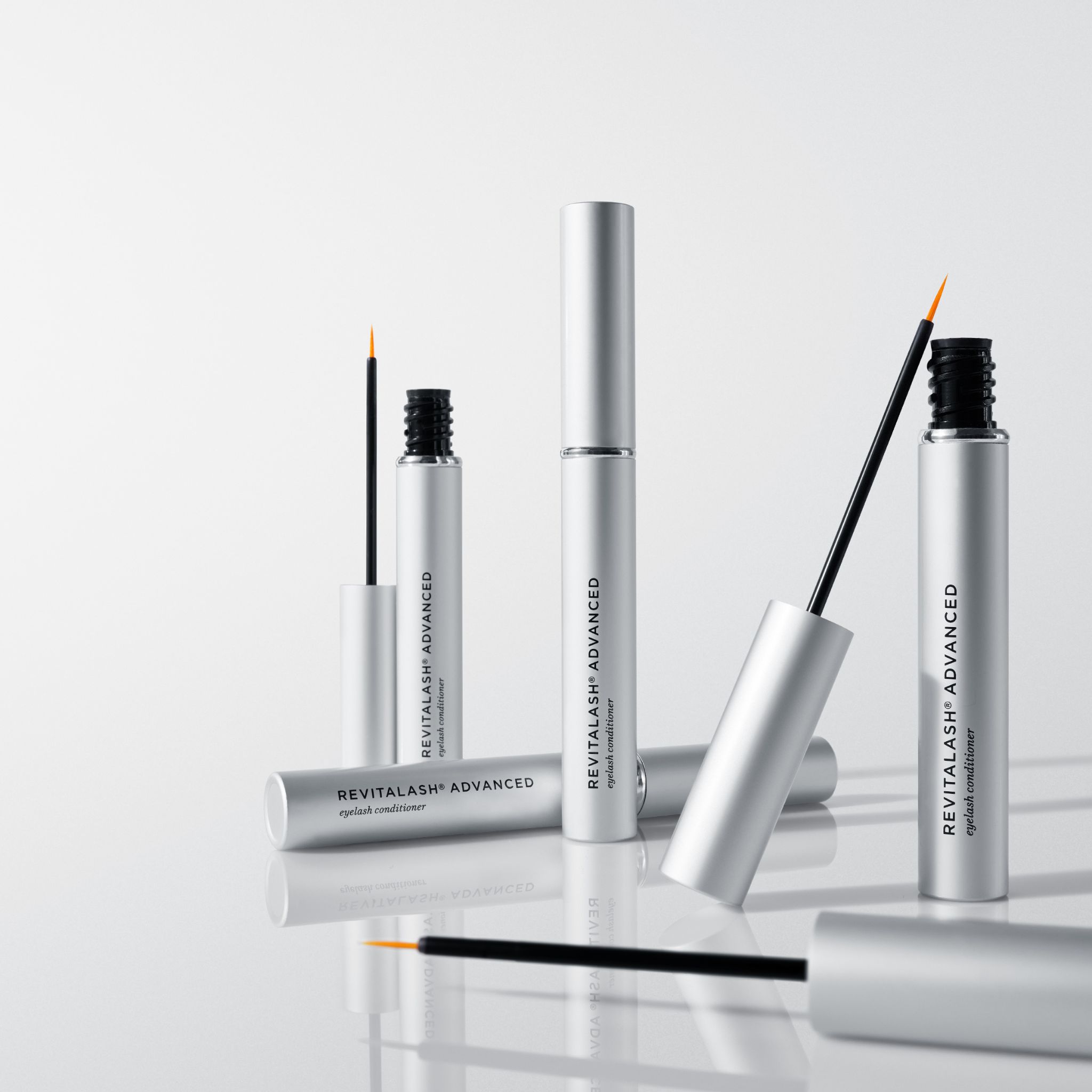 Mehrere silberne Flaschen mit Revitalash Advanced Eyelash Conditioner und Applikatoren.