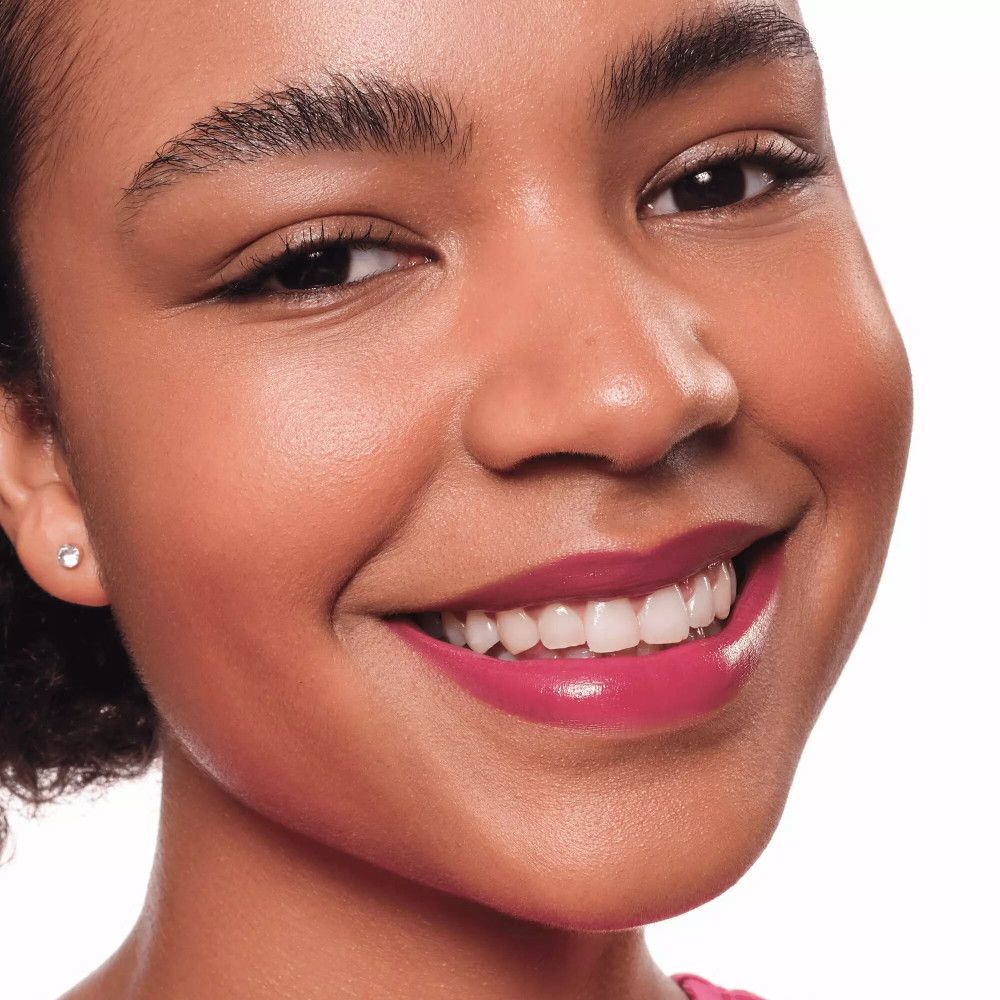 Porträt einer Frau mit pink getönten Lippen. Sie lächelt. Ohrring.