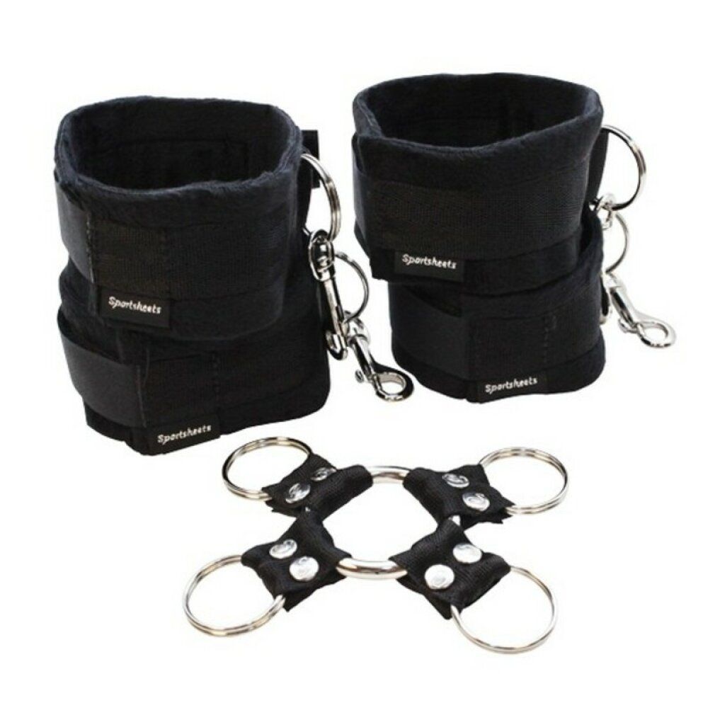 Zwei schwarze Manschetten mit Klettverschluss und Karabinerhaken. Ein schwarzes Verbindungsstück mit Ringen.