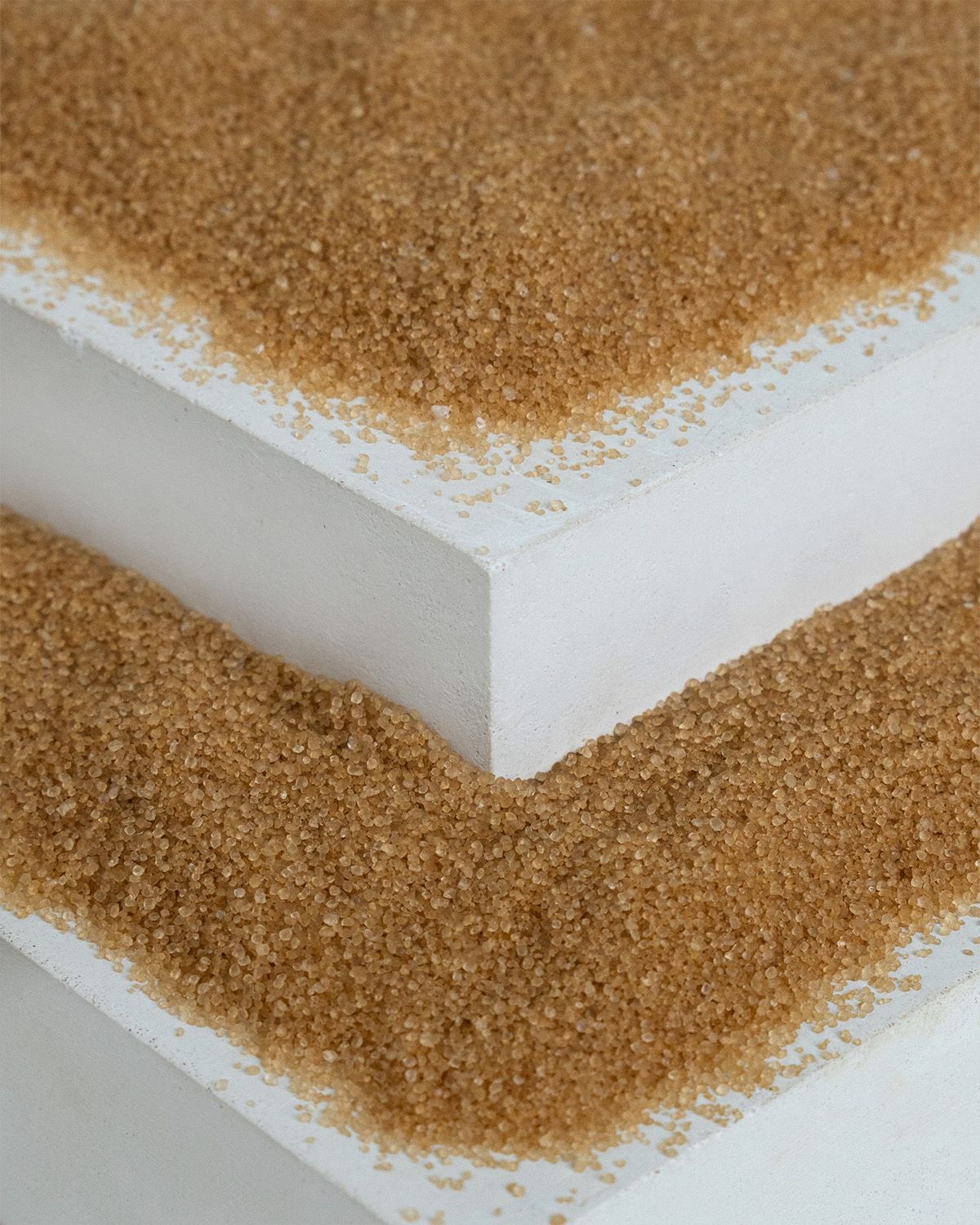 Feines, bronzefarbenes Erythritol-Granulat auf weißen Oberflächen.