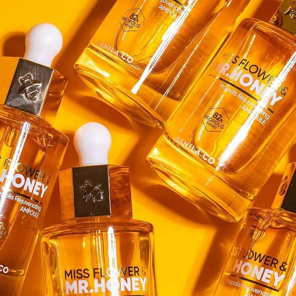 Mehrere Glasflaschen mit goldener Flüssigkeit und Pipettenverschluss. Beschriftung: 'Miss Flower & Mr. Honey'.