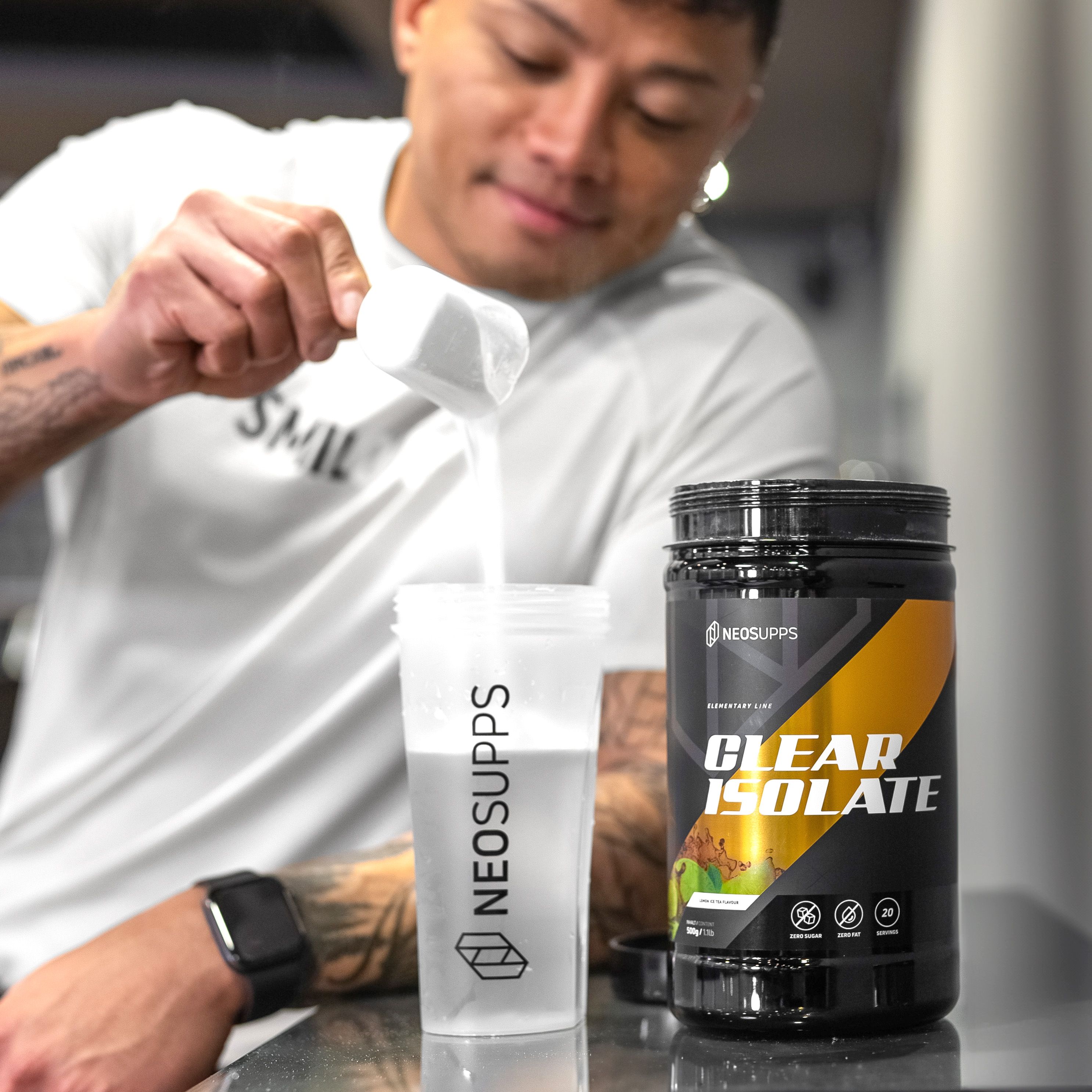 Mann gießt Pulver aus einem Messbecher in einen Shaker. Aufschrift NEOSUPPS. Dose mit gelbem Akzent und CLEAR ISOLATE.