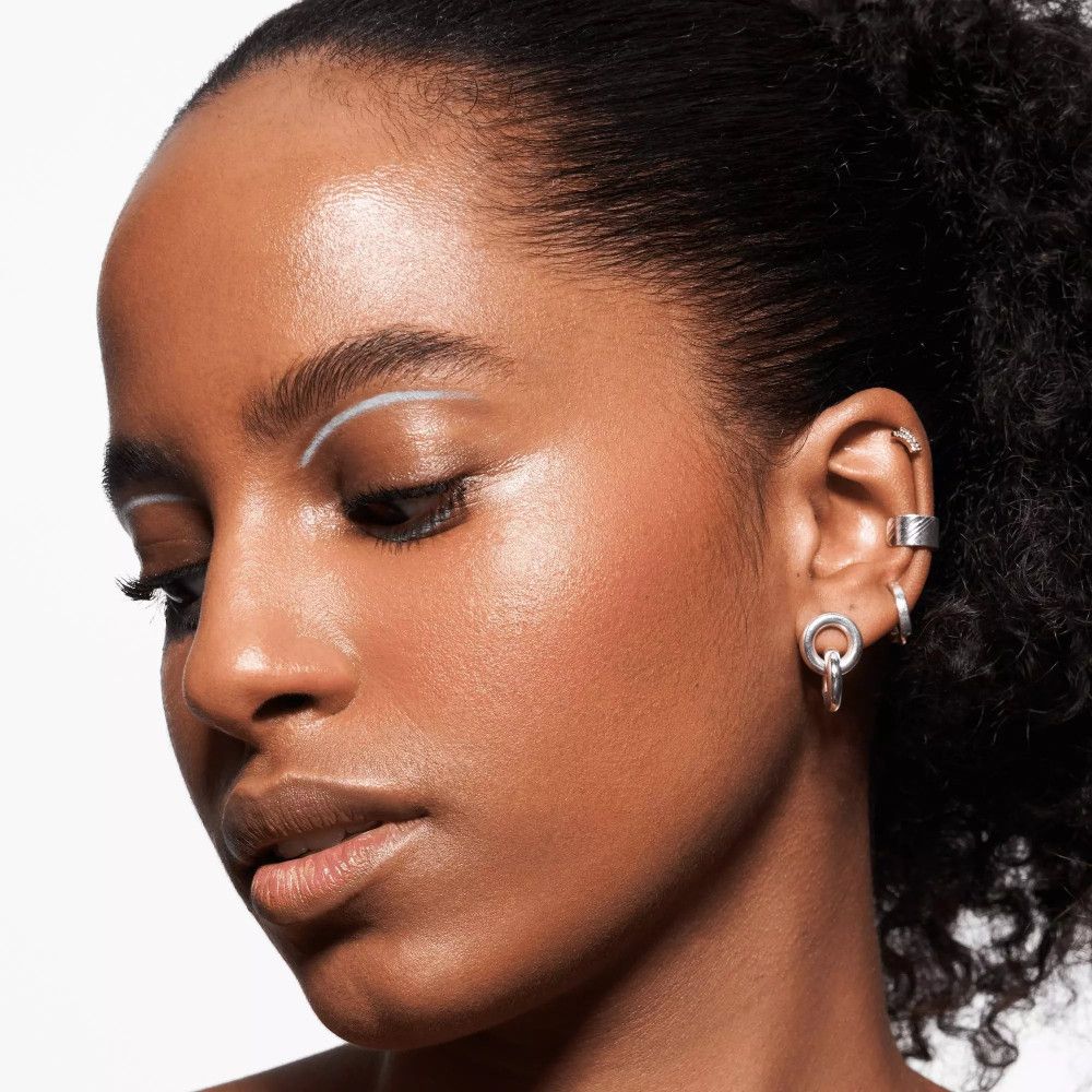 Nahaufnahme einer Frau mit weißem Eyeliner. Sie trägt Ohrringe.