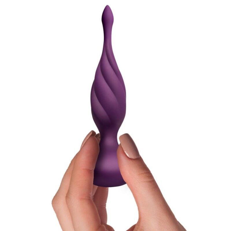 Lila Anal Stimulator mit gerilltem Design und breiter Basis, daneben eine Fernbedienung. Produktverpackung im Hintergrund.