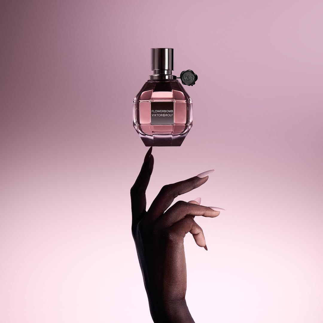 Parfümflakon mit rosafarbenem Inhalt. Aufschrift: Flowerbomb Viktor & Rolf. Hand.