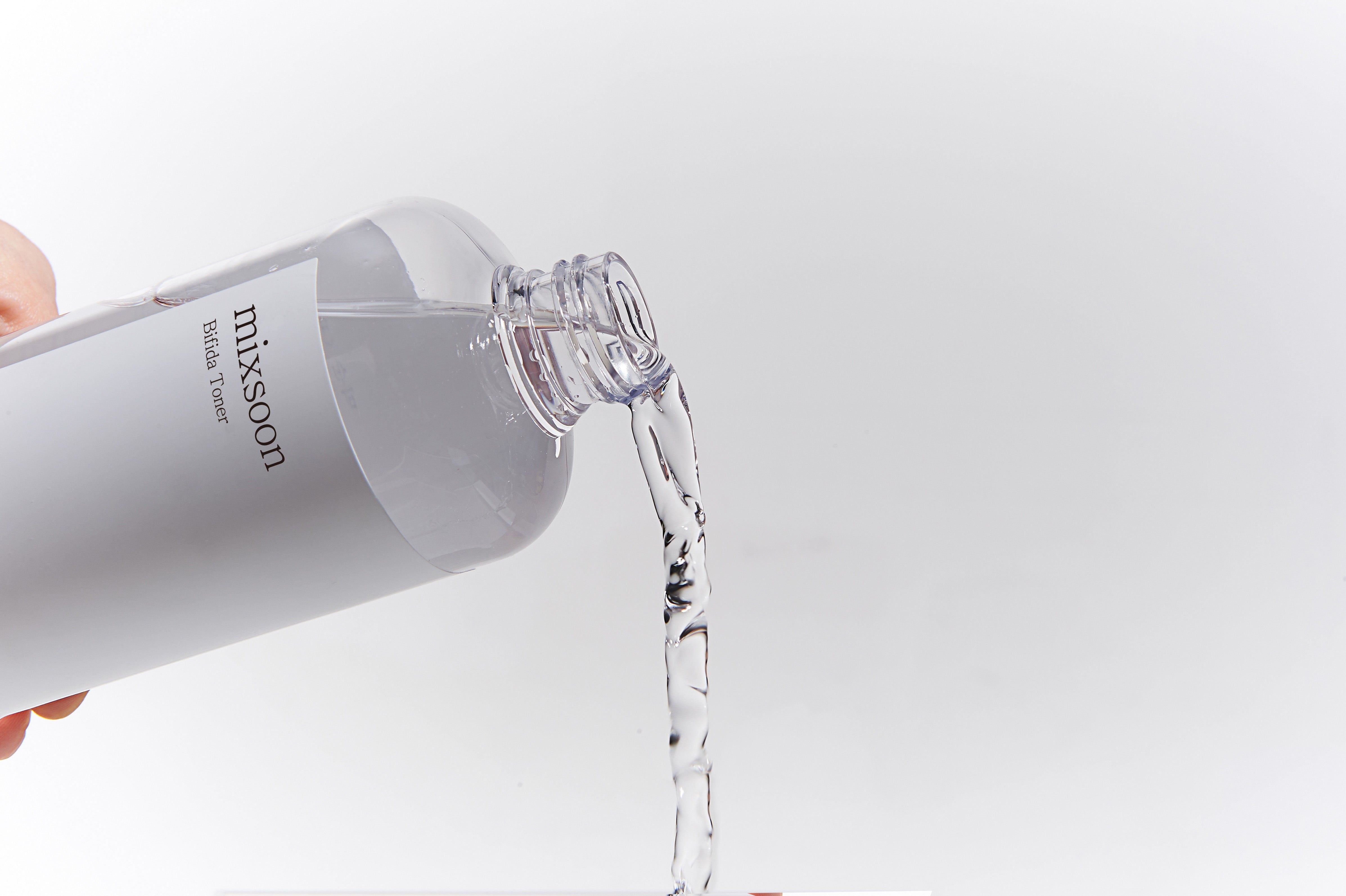 Eine Flasche, aus der Flüssigkeit in einen Behälter gegossen wird. Auf der Flasche steht "mixsoon".