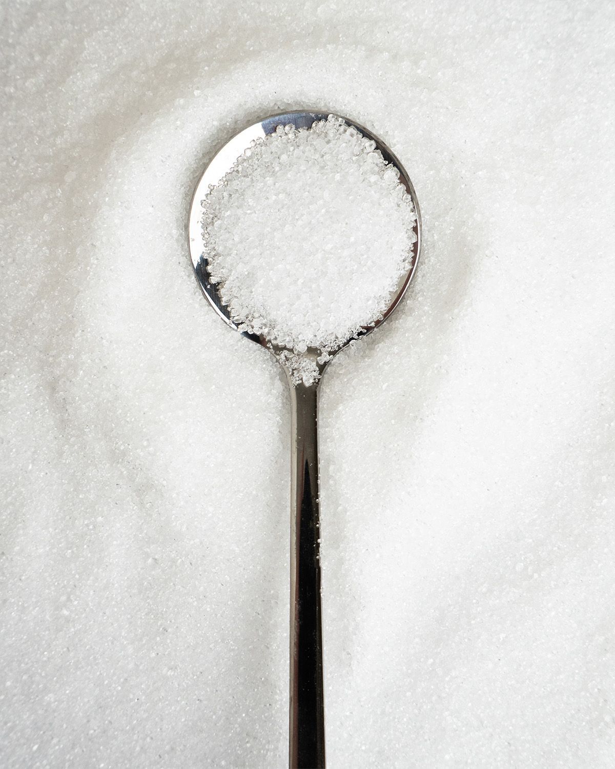 Ein Löffel mit feinem, weißem Erythritol-Kristallpulver.