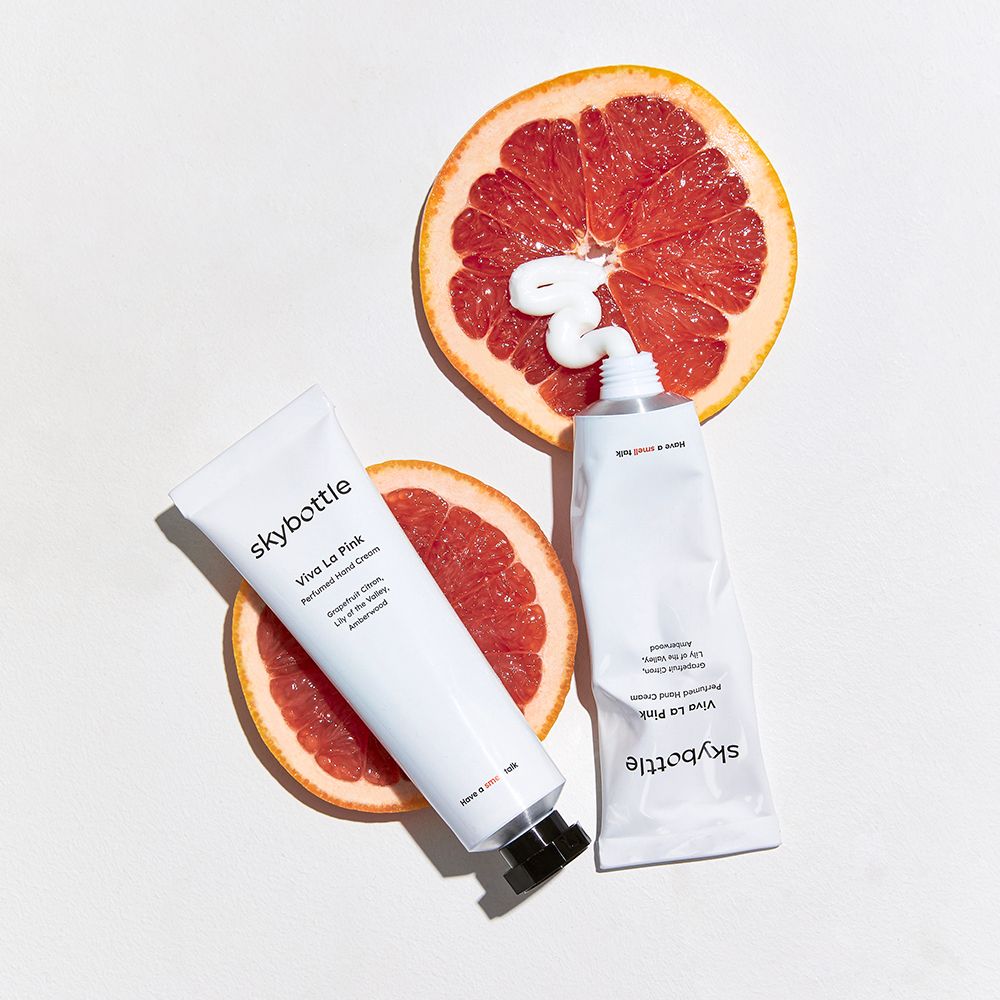 Zwei Tuben und zwei Grapefruit-Hälften. Eine Tube mit Creme, eine ohne. Aufschrift: skybottle, Viva La Pink.