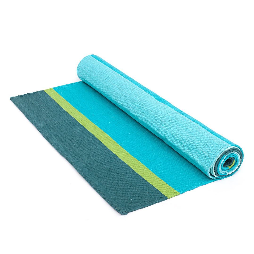 Gerollte Yoga-Matte aus Baumwolle in Petrol, Türkis und Grün. Teilweise ausgerollt, zeigt Streifenmuster.