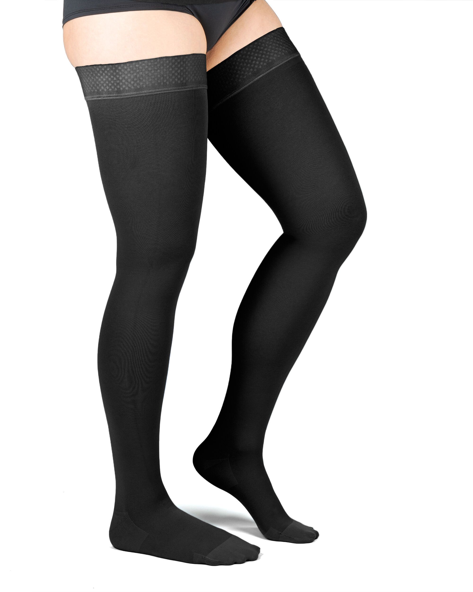 Beine mit schwarzen Kompressionsstrümpfen. Oberschenkelstrümpfe. Schwarze Strümpfe mit breitem Bund. Stehende Person.