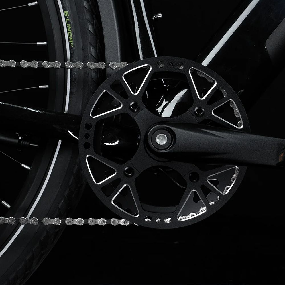 Fahrradkette und Kettenblatt. Schwarzes Kettenblatt mit Löchern. Schwarzer Hintergrund.