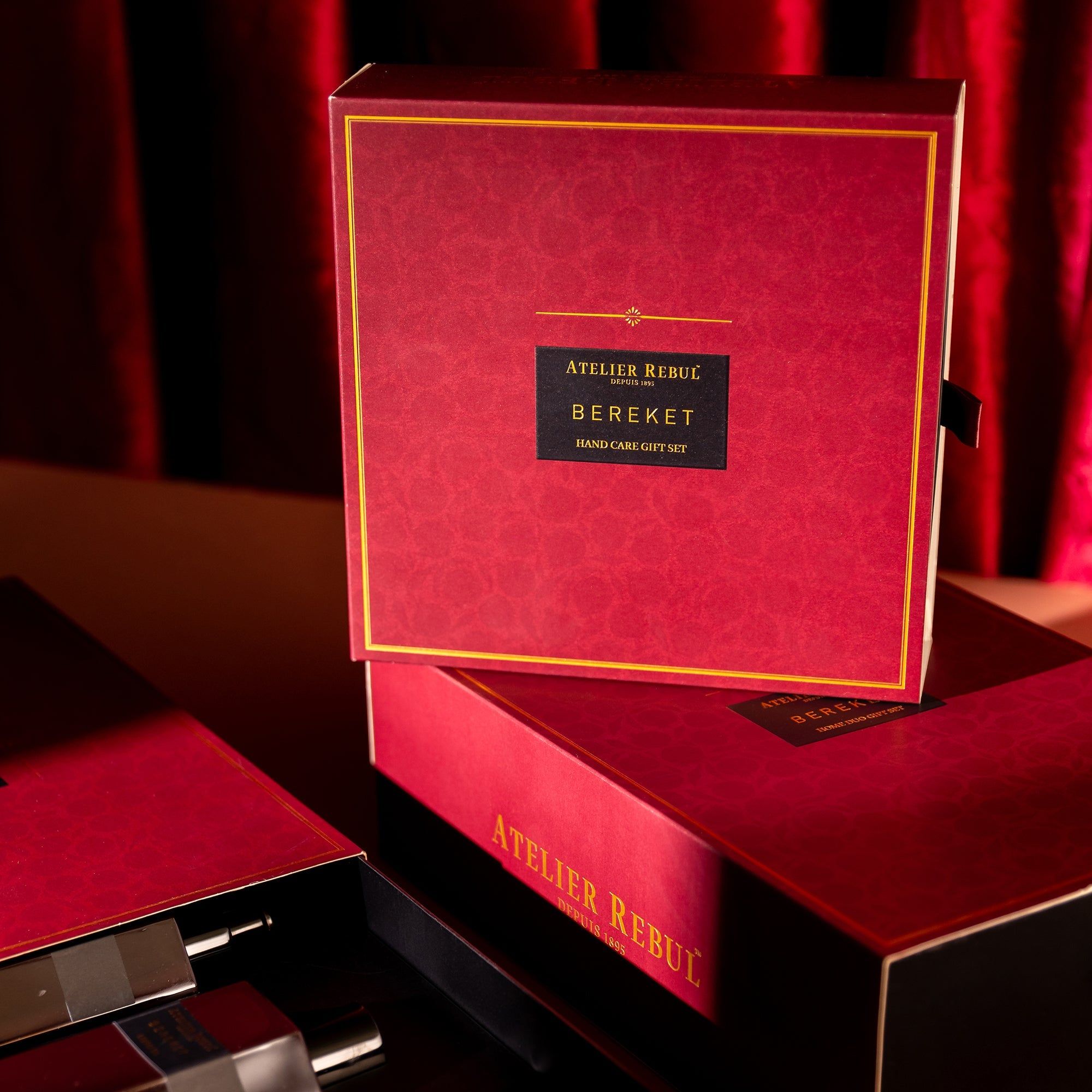 Rote Geschenkbox mit goldfarbenem Rand. Schwarzes Etikett mit Text: Atelier Rebul, Bereket, Hand Care Gift Set. Geöffnet, weitere Boxen sichtbar.