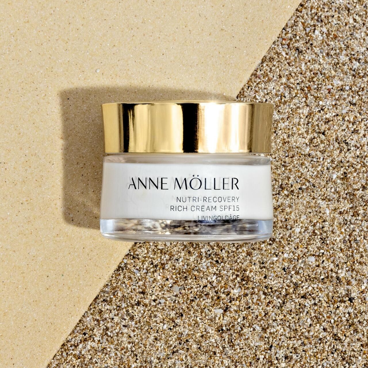 Creme-Glas auf Sand. Aufschrift: ANNE MÖLLER, Nutri-Recovery Rich Cream SPF15, Livingoldâge.