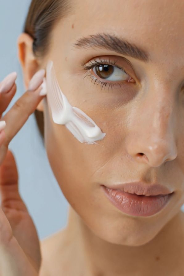 Frau trägt Creme auf ihr Gesicht auf. Creme auf der Haut sichtbar.