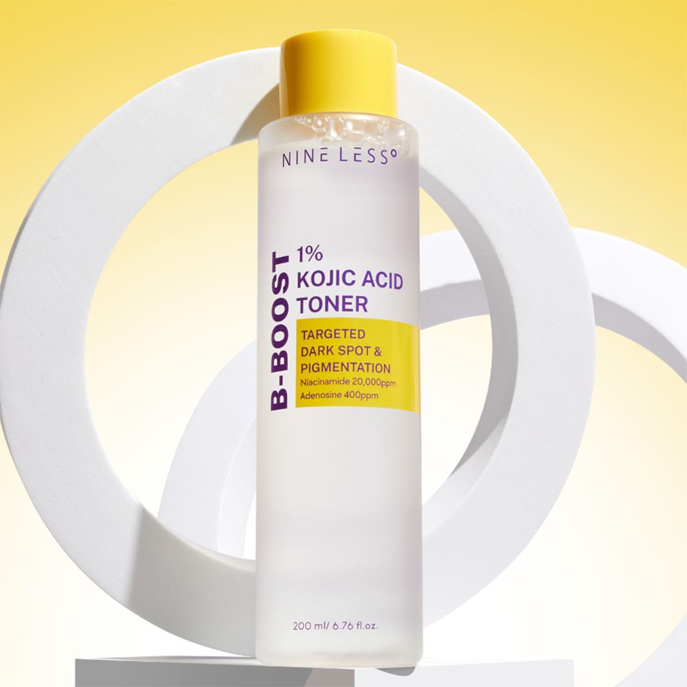 Klarflasche mit gelbem Deckel. Aufschrift: NINE LESS, B-Boost 1% Kojic Acid Toner. 200 ml. Auf weißem Hintergrund.