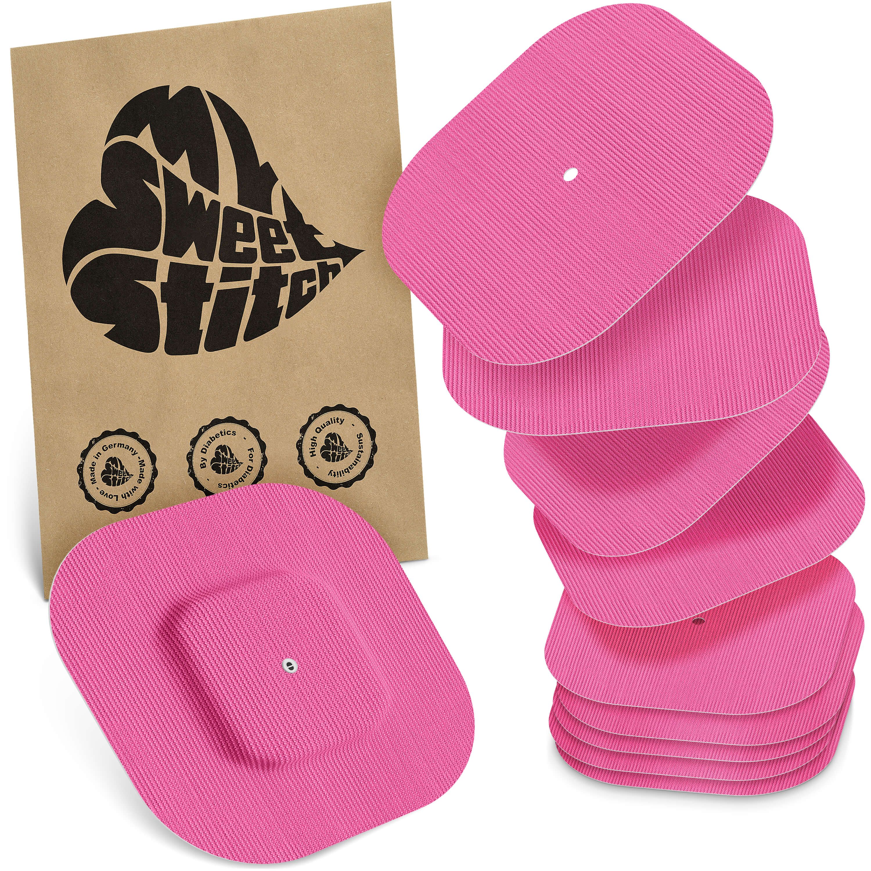 Rosa quadratische Pflaster mit einem kleineren, quadratischen Pflaster in der Mitte. Einige Pflaster sind gestapelt. Eine braune Papiertüte mit Logo.