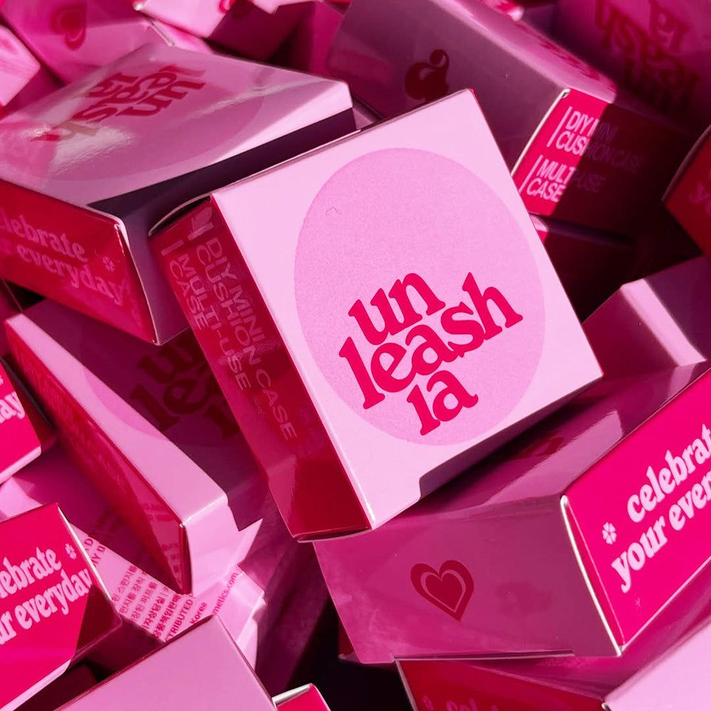 Rosa Verpackung mit 'unleashia' Logo und Text. Mehrere Schachteln liegen zusammen.
