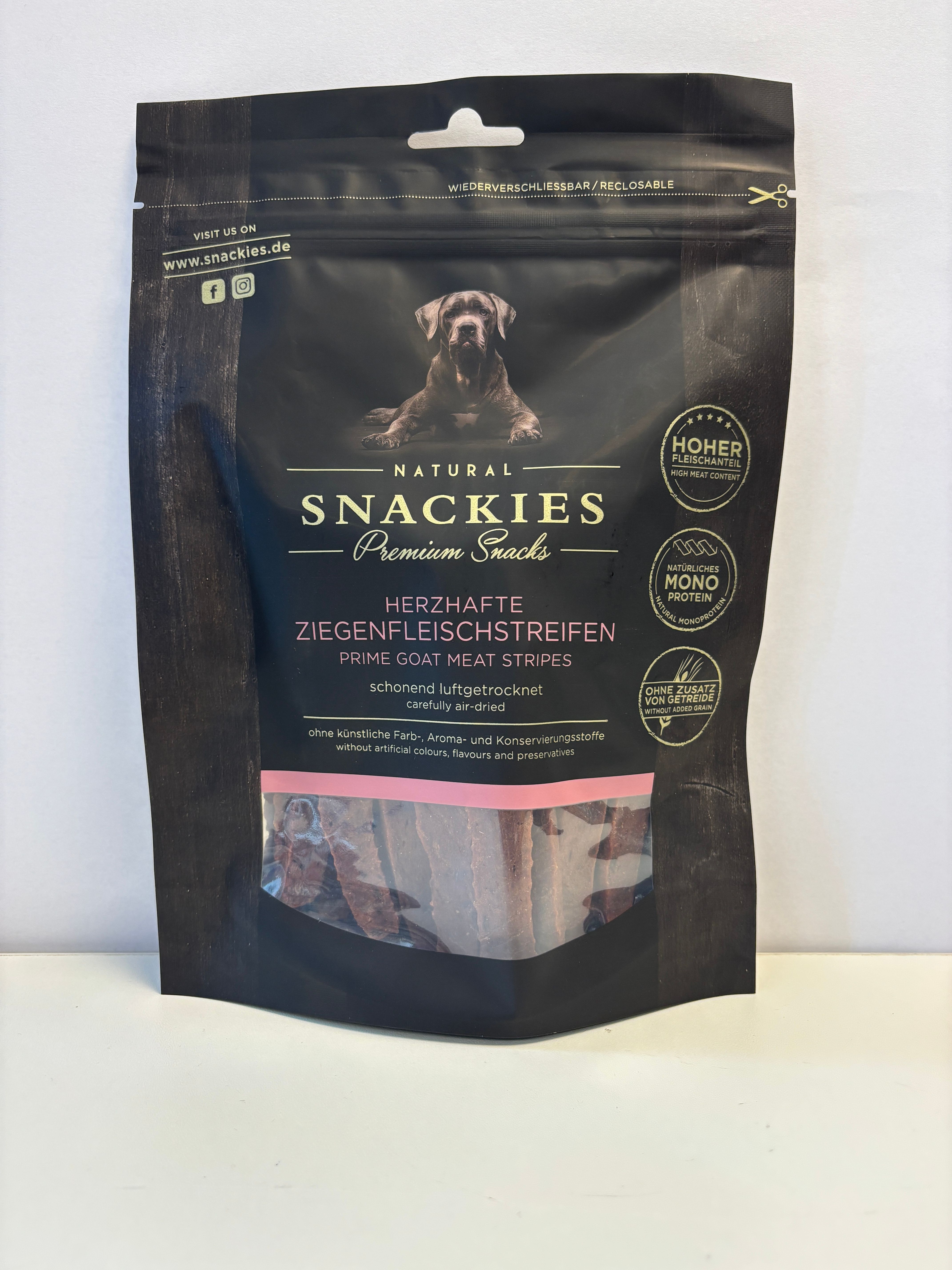 Verpackung mit Ziegenfleischstreifen. Schwarze Verpackung mit Produktnamen und Logo. Sichtfenster zeigt getrocknete Streifen.