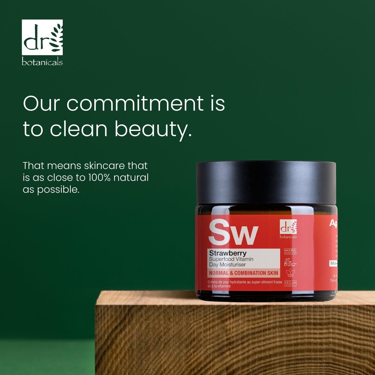 Creme-Dose mit schwarzem Deckel auf Holzblock. Aufschrift: Strawberry Superfood Vitamin C Day Moisturiser. Marke: Dr Botanicals. Text: Our commitment is to clean beauty.