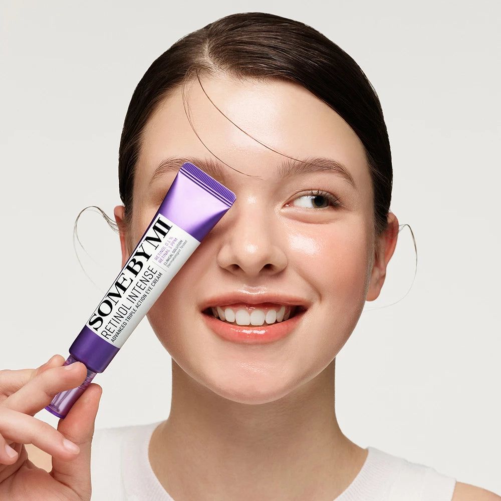 Frau hält Tube Augencreme vor Auge. Auf der Tube steht SOMEBYMI Retinol Intense Advanced Triple Action Eye Cream.