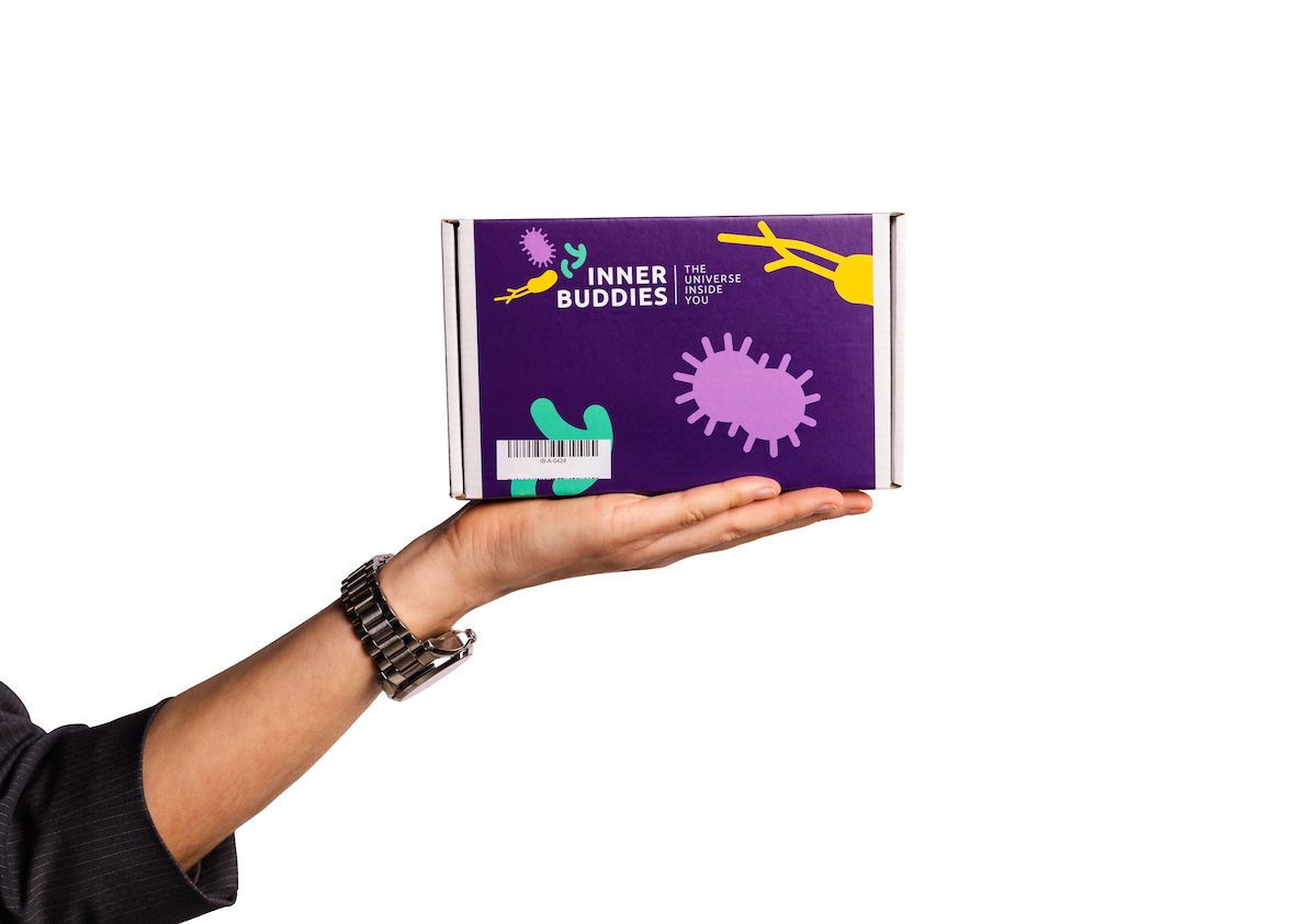 Kartonverpackung mit Logo und Illustrationen, gehalten von einer Hand. Aufschrift: Inner Buddies.