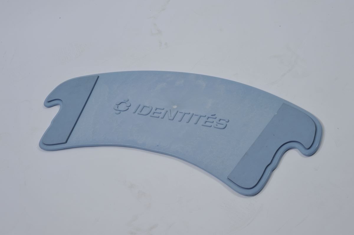 Blaues Transferbrett mit abgerundeter Form und zwei Aussparungen. Aufschrift: IDENTITÉS.