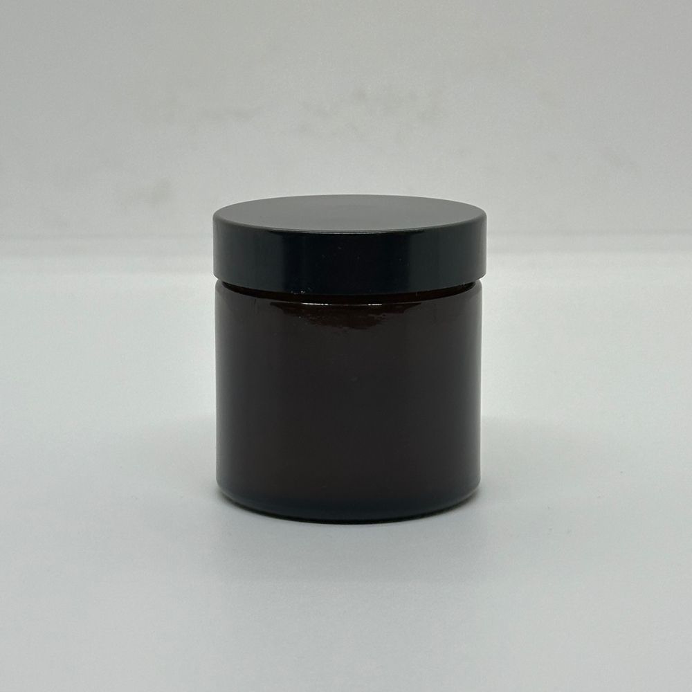 Braune Glasdose mit schwarzem Deckel. Zylindrische Form. Auf weißem Hintergrund.