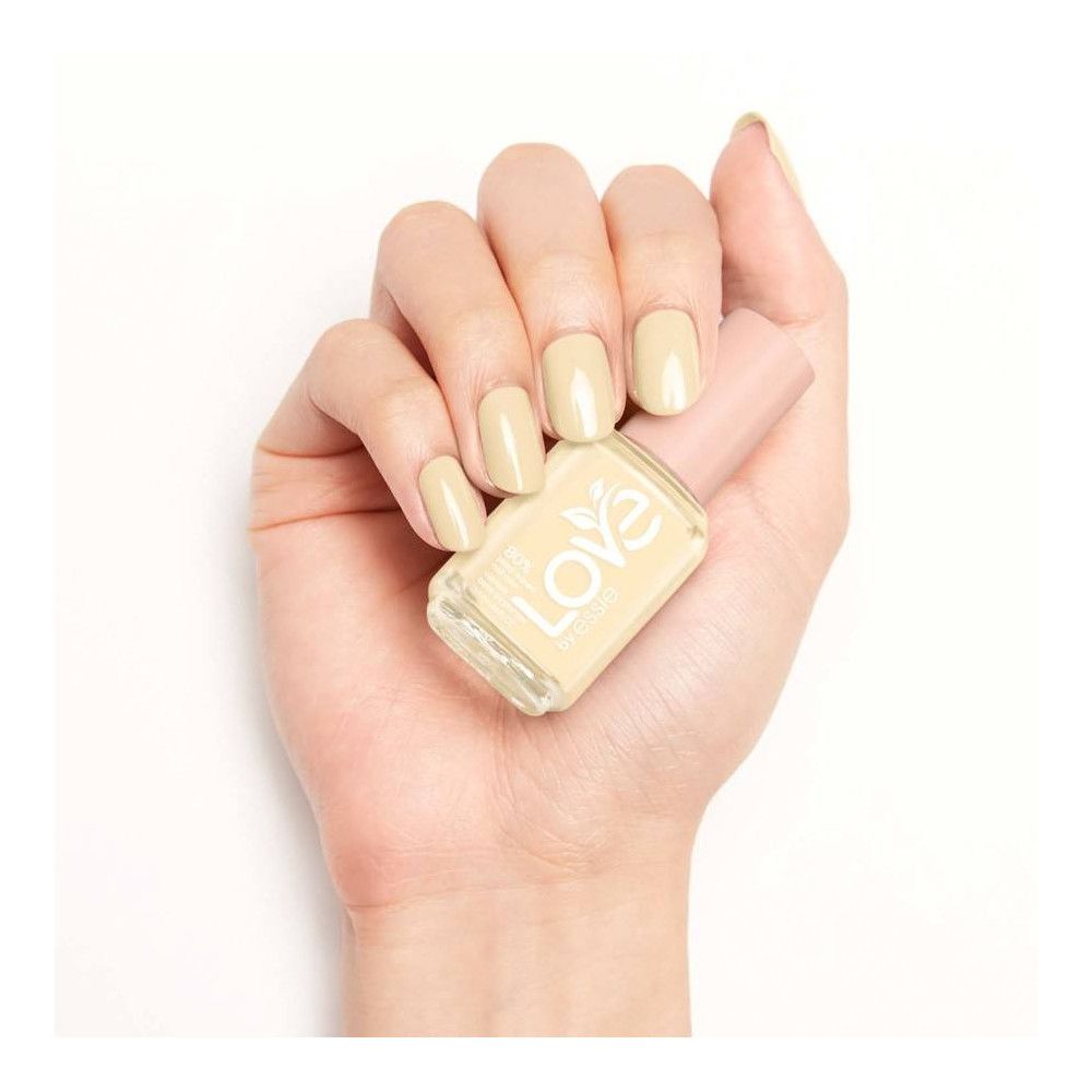 Hand mit lackierten Nägeln und Nagellackflasche. Flasche mit rosa Deckel, helle Farbe.