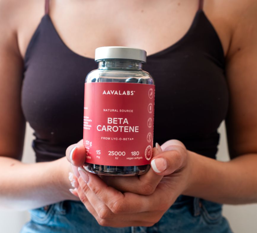 Person hält Aavalabs Beta Carotene Flasche. 180 vegane Softgels, 25.000 IE.