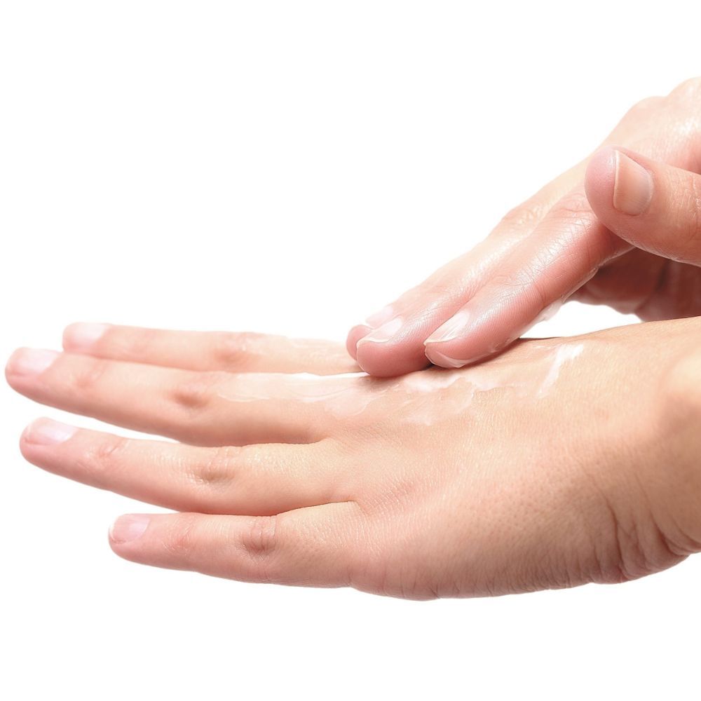 Nahaufnahme einer Hand, die Creme auf die andere Hand aufträgt. Haut ist sichtbar.