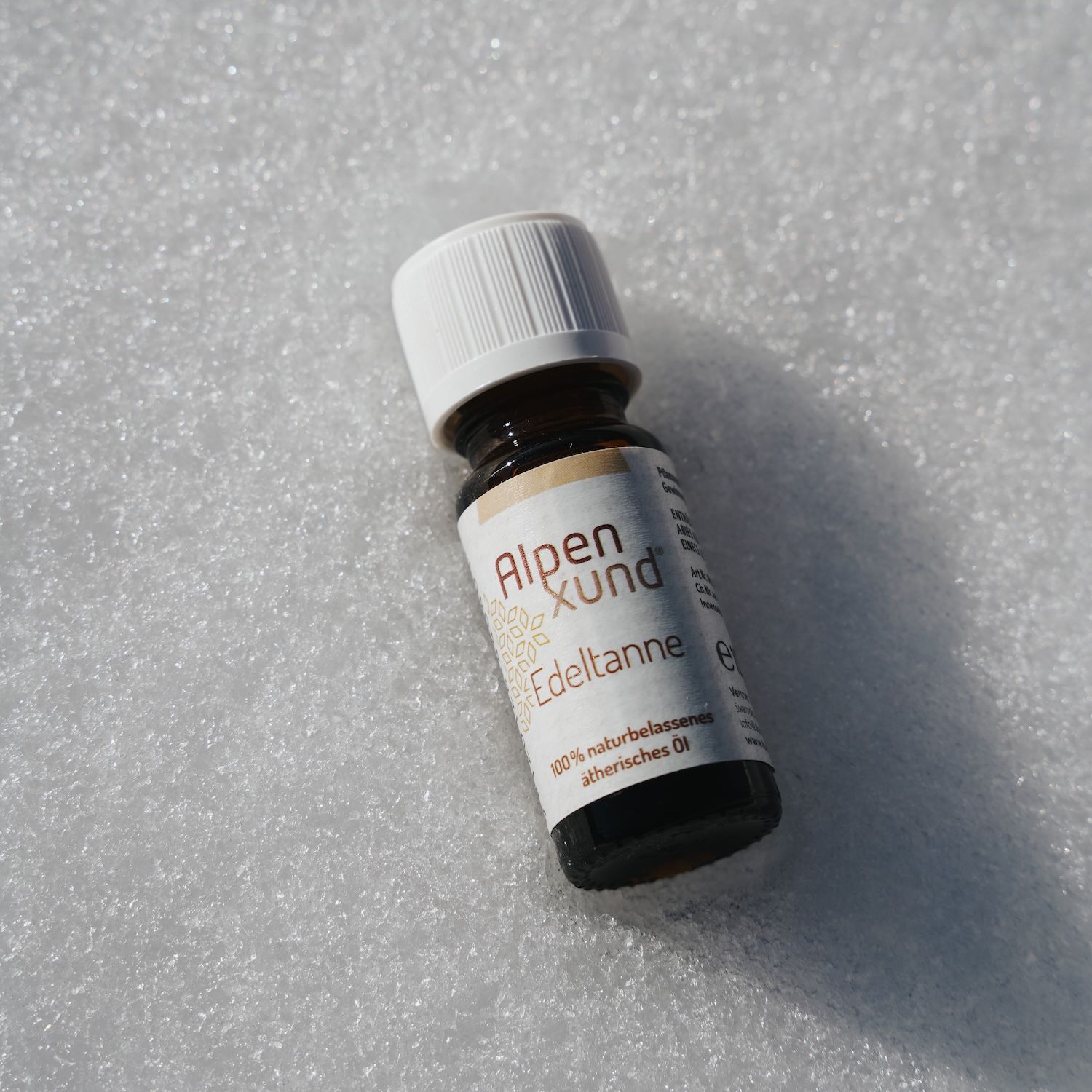 Braune Glasflasche mit weißem Deckel. Etikett mit AlpenXund und Edeltanne. Auf weißem Untergrund.