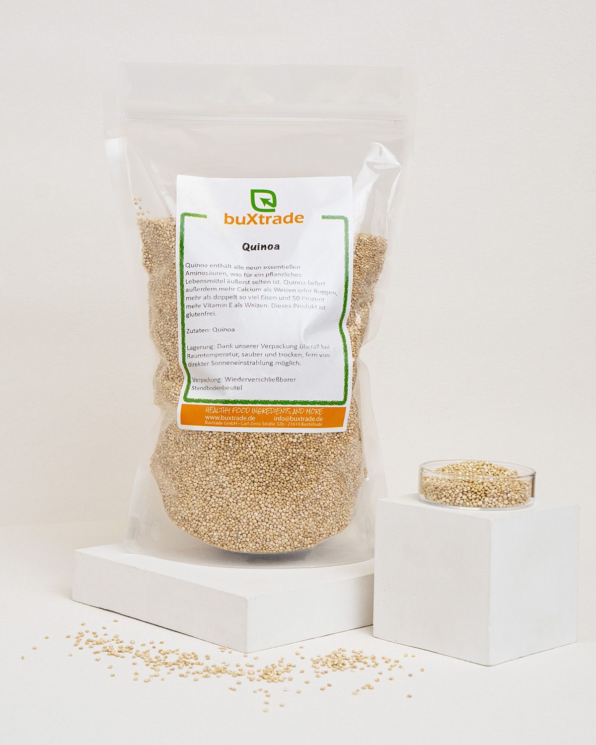 Transparente Tüte mit buXtrade Quinoa. Daneben eine kleine Schale mit Quinoa auf einem weißen Podest. Hintergrund weiß.