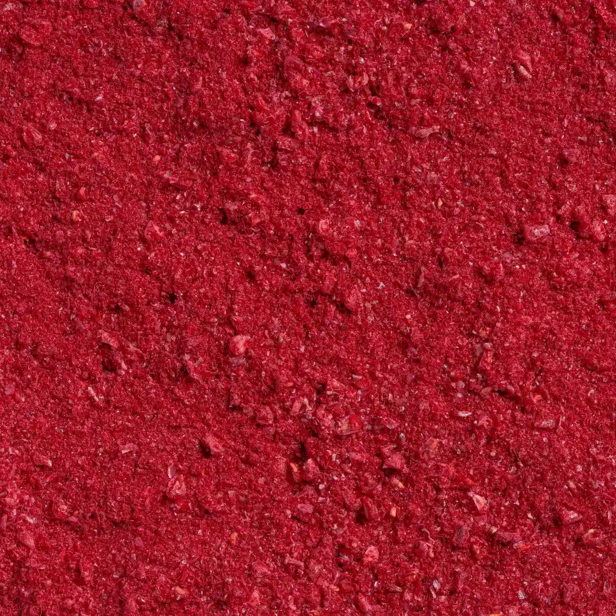 Nahaufnahme von gefriergetrocknetem Himbeerpulver. Rote, körnige Textur.