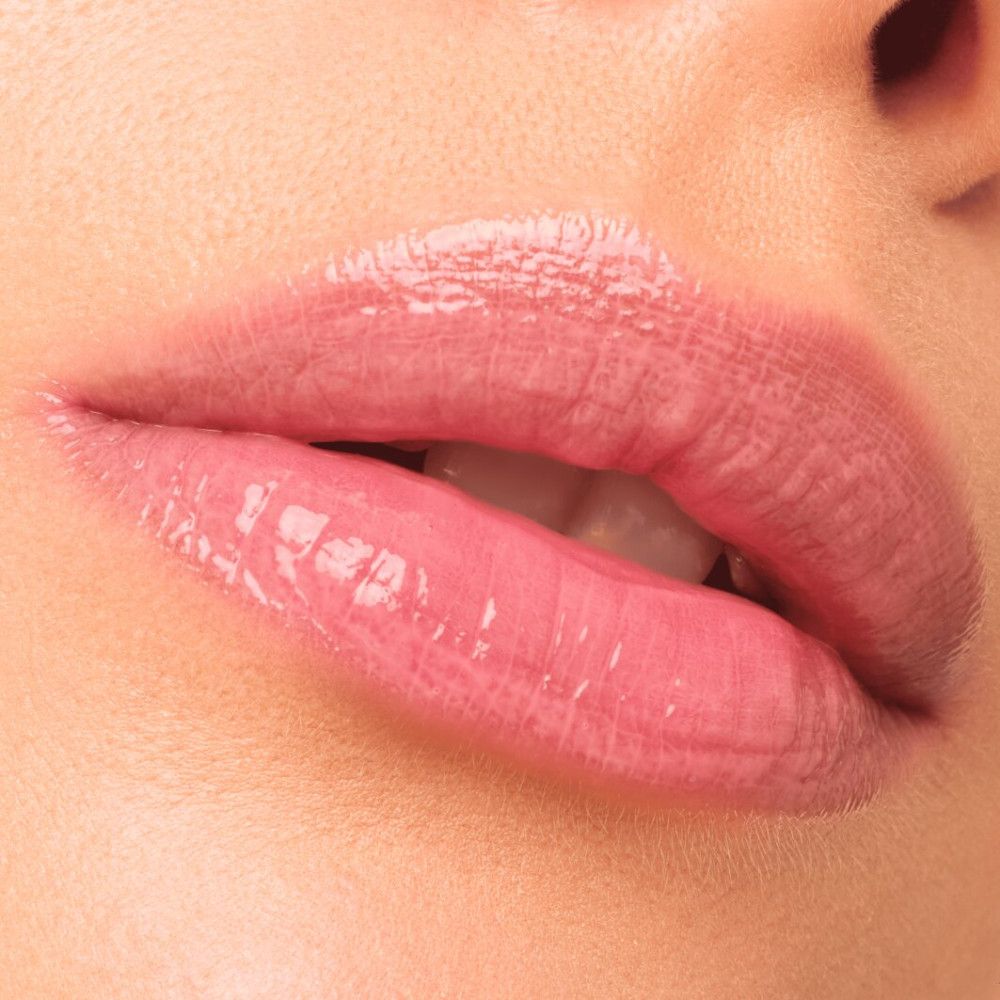 Nahaufnahme von Lippen mit aufgetragenem, glänzendem Lipgloss. Rosa Farbton, glänzendes Finish.