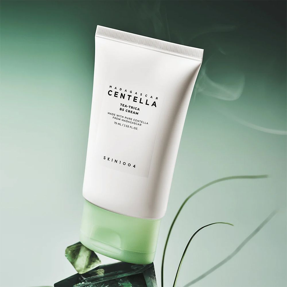 Tube SKIN1004 Centella Tea-Trica B5 Cream auf grünen Steinen.