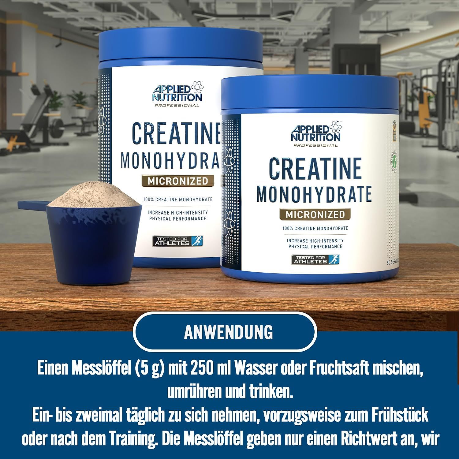 Zwei Dosen Applied Nutrition Kreatin Monohydrat und ein Messlöffel mit Pulver auf einem Holztisch.