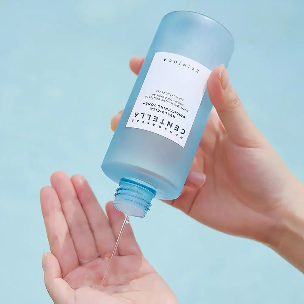 Blau-transparente Flasche, Flüssigkeit wird in die Hand gegossen. Aufschrift: SKIN1004, MADAGASCAR CENTELLA, HYALU-CICA.