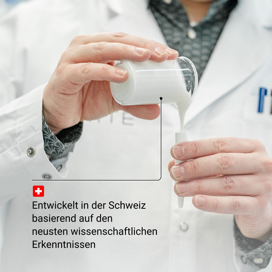 Person gießt Serum in einen Behälter. Laborumgebung. Text: Entwickelt in der Schweiz.