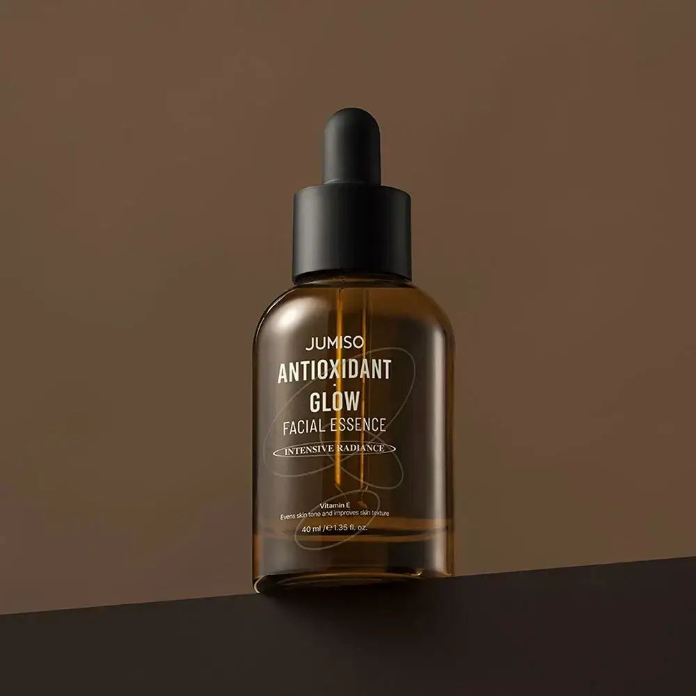 Braune Glasflasche mit schwarzem Deckel und Pipette. Aufschrift: JUMISO ANTIOXIDANT GLOW FACIAL ESSENCE.
