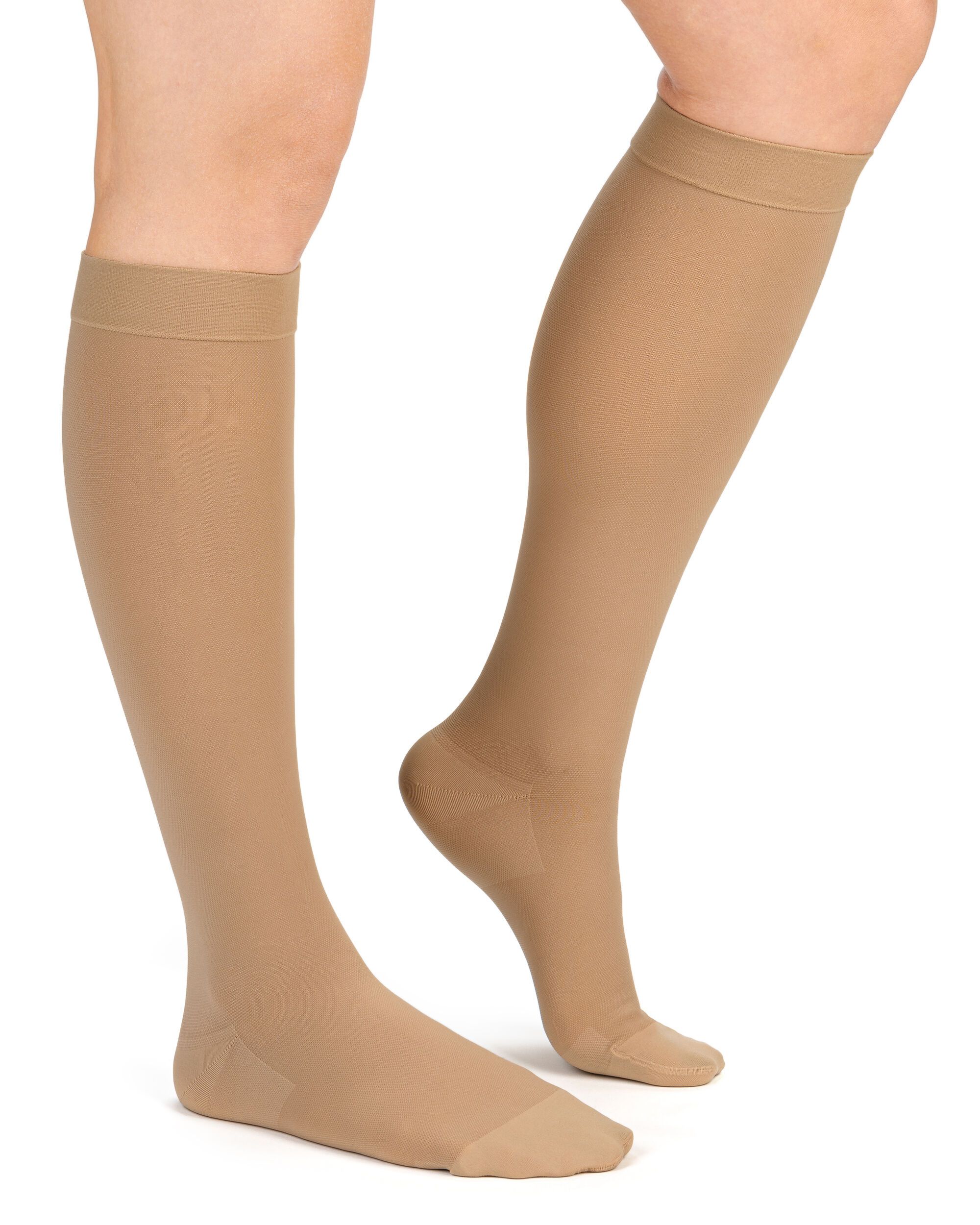 Beine mit hautfarbenen Kompressionskniestrümpfen. Strümpfe reichen bis zum Knie.