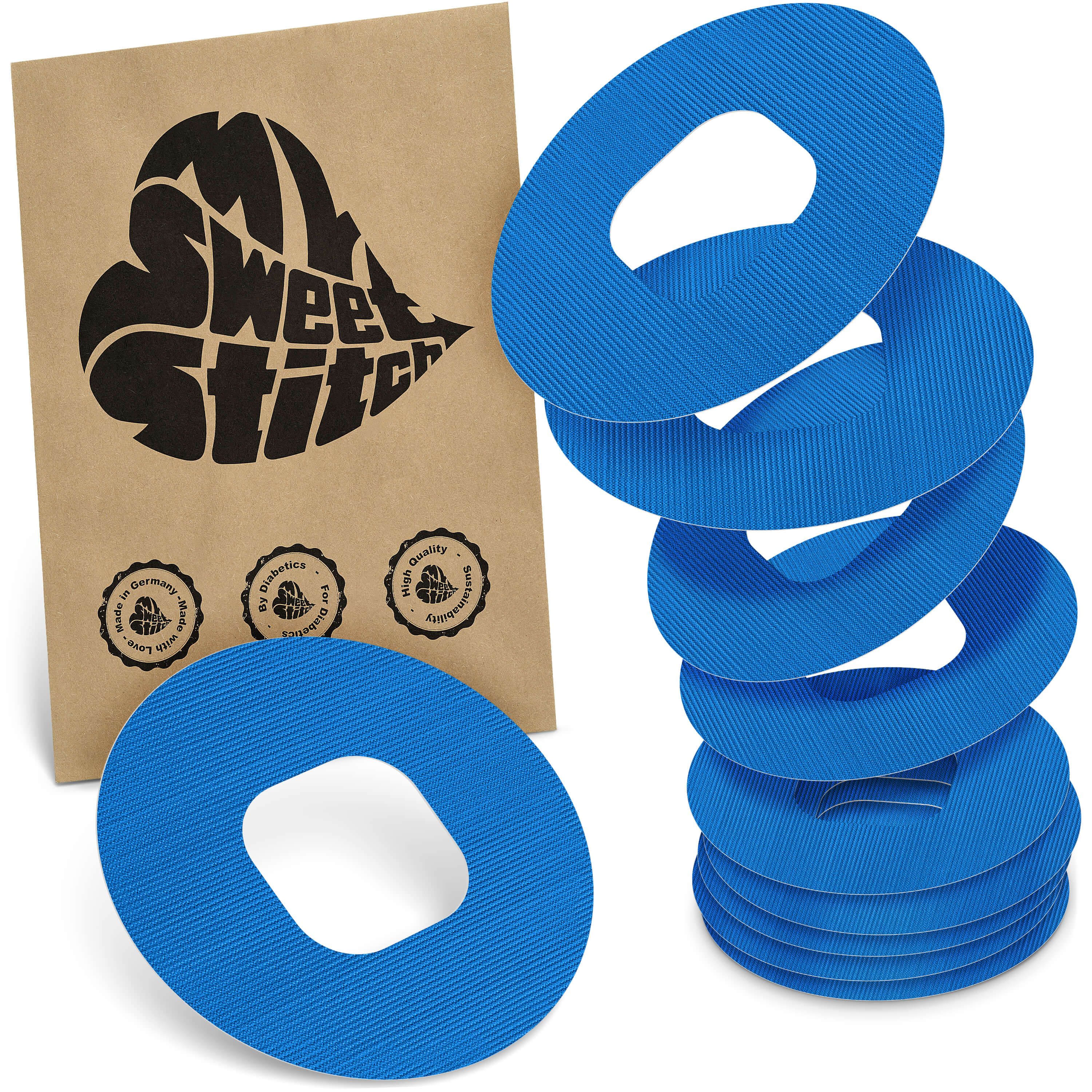 Blaue, ringförmige Pflaster mit ovaler Aussparung. Auf brauner Verpackung steht "My Sweet Stitch".