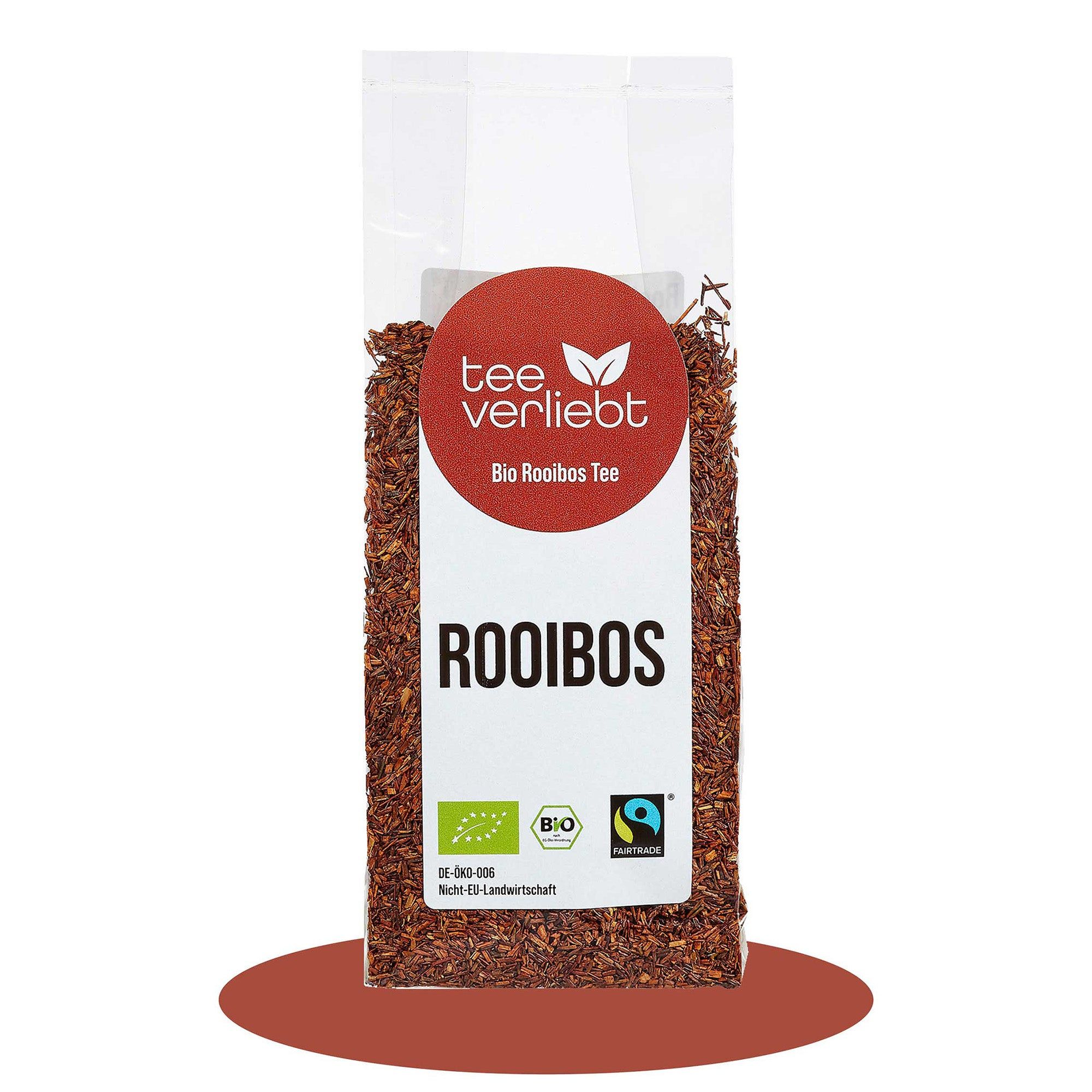 Transparente Tüte mit losem Rooibos-Tee. Runder Aufkleber mit "tee verliebt" und "Bio Rooibos Tee". Bio-Siegel und Fairtrade-Logo.