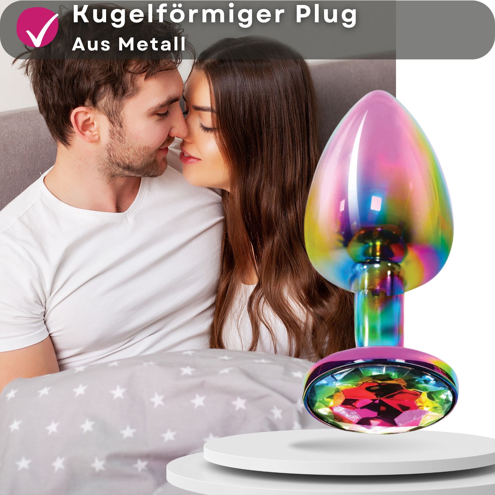 Analplug, mehrfarbig, aus Metall, mit Zierstein. Frau im Hintergrund. Produkt auf Podest.