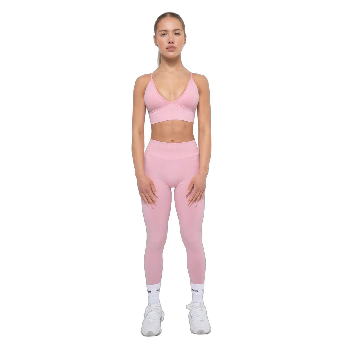 Frau in Babyrosa nahtloser Sportbekleidung: High-Rise-Leggings und passender BH.