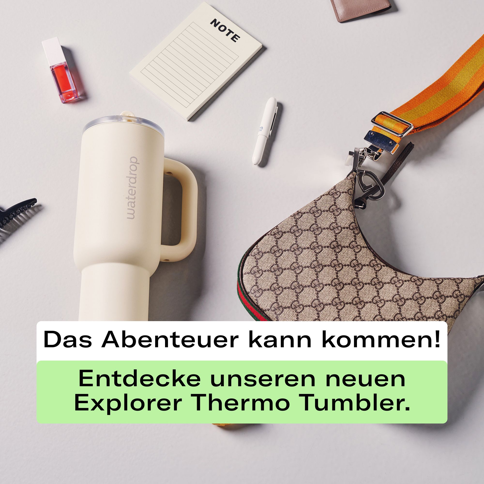 Off-white Thermobecher XL mit Henkel neben Handtasche und Kosmetika.