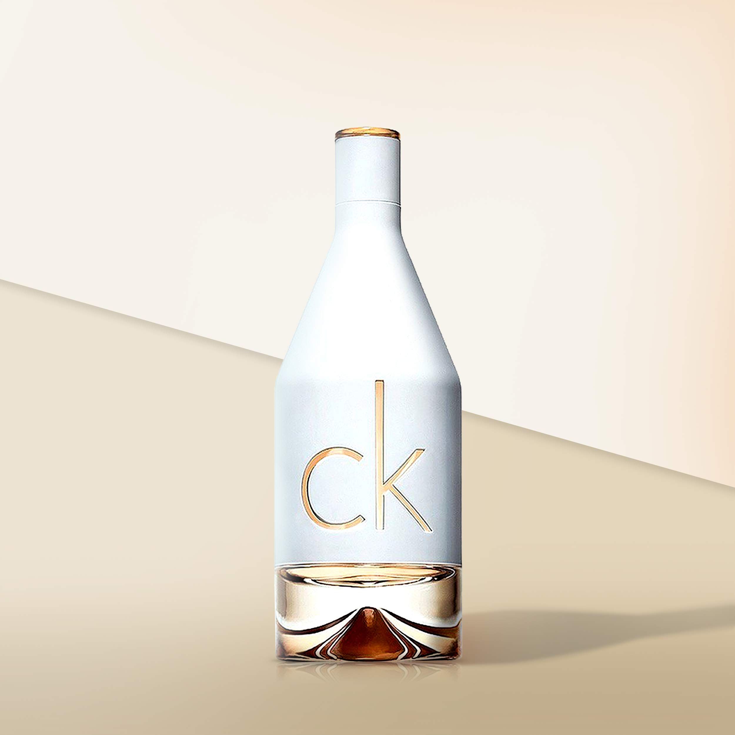Calvin Klein In2u Parfümflasche, weißes Glas, goldfarbene Schrift. Unterteil mit Flüssigkeit gefüllt. CK-Logo.