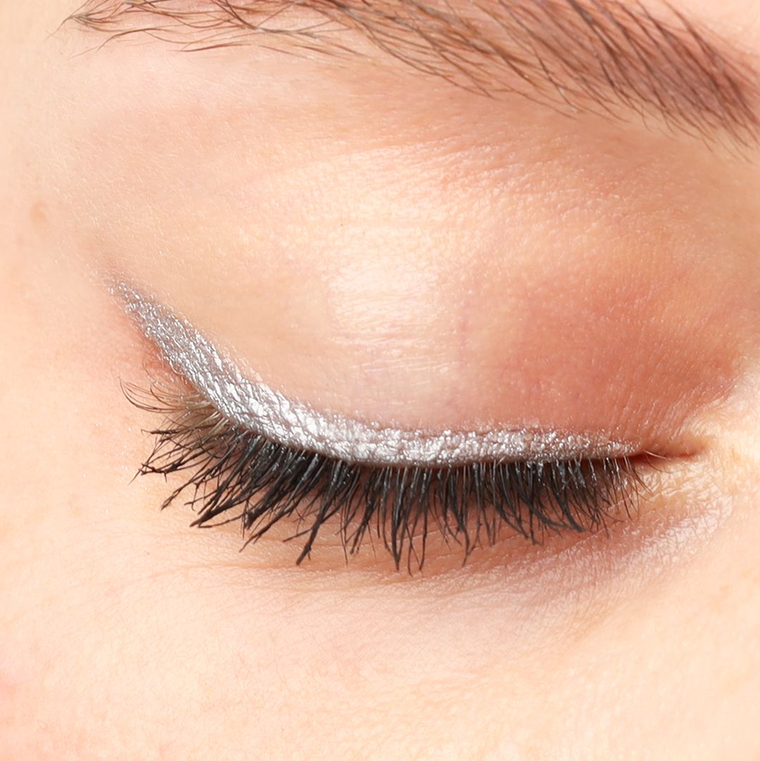 Geschlossenes Auge mit silbernem Kajal-Eyeliner auf dem oberen Augenlid. Nahaufnahme.